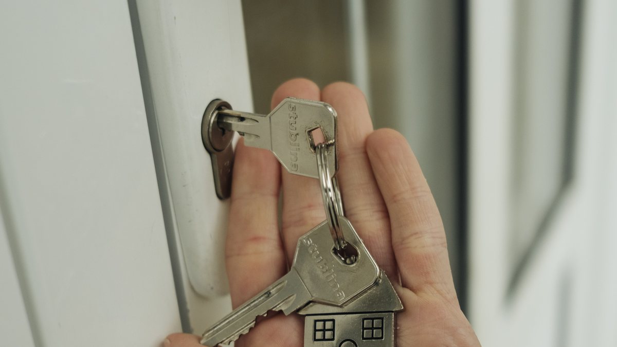 A hand holding house keys in front of a door handle